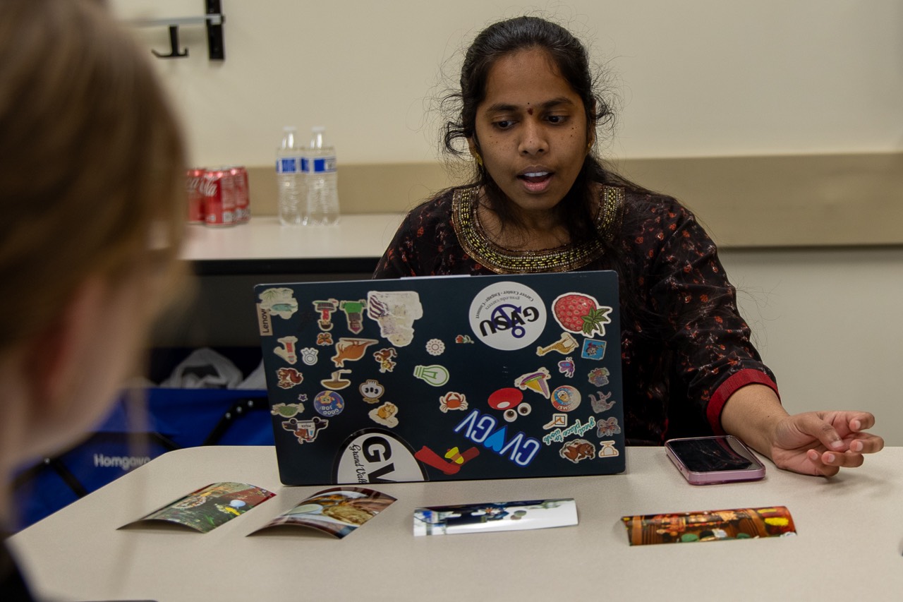 Person speaking to group with laptop and photos